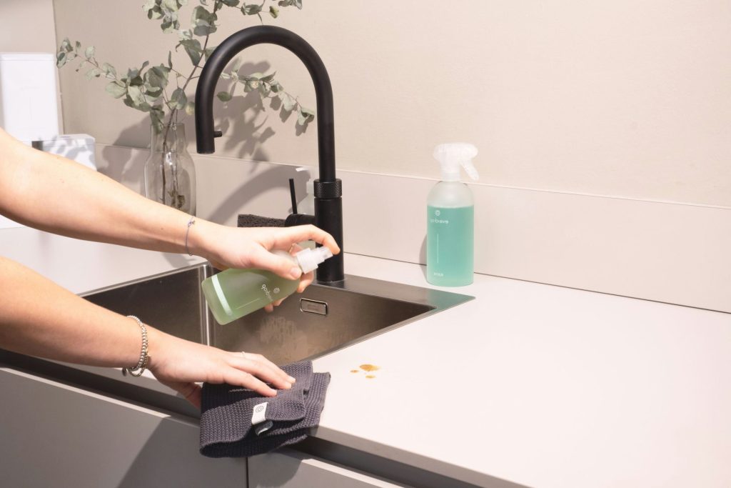 a woman is cleaning a kitchen sink with a rag